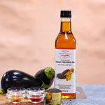 Bottle of Indiyeah cold pressed oil with ingredients on a wooden board against a beige background